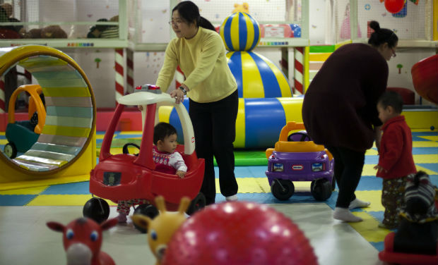Parents play with their children at a kid's play area in a shopping mall in Beijing - AP/File photo Parents play with their children at a kid's play area in a shopping mall in Beijing - AP/File photo